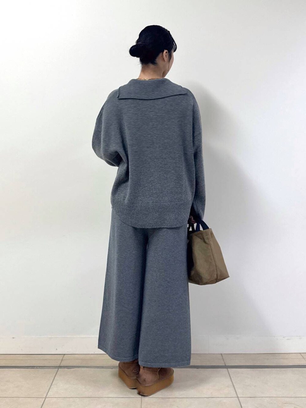 イエロー系のトートバッグ、イエロー系のブーツ、グレー系のニット/セーターを着用したレディースの冬コーディネートの3枚目の写真