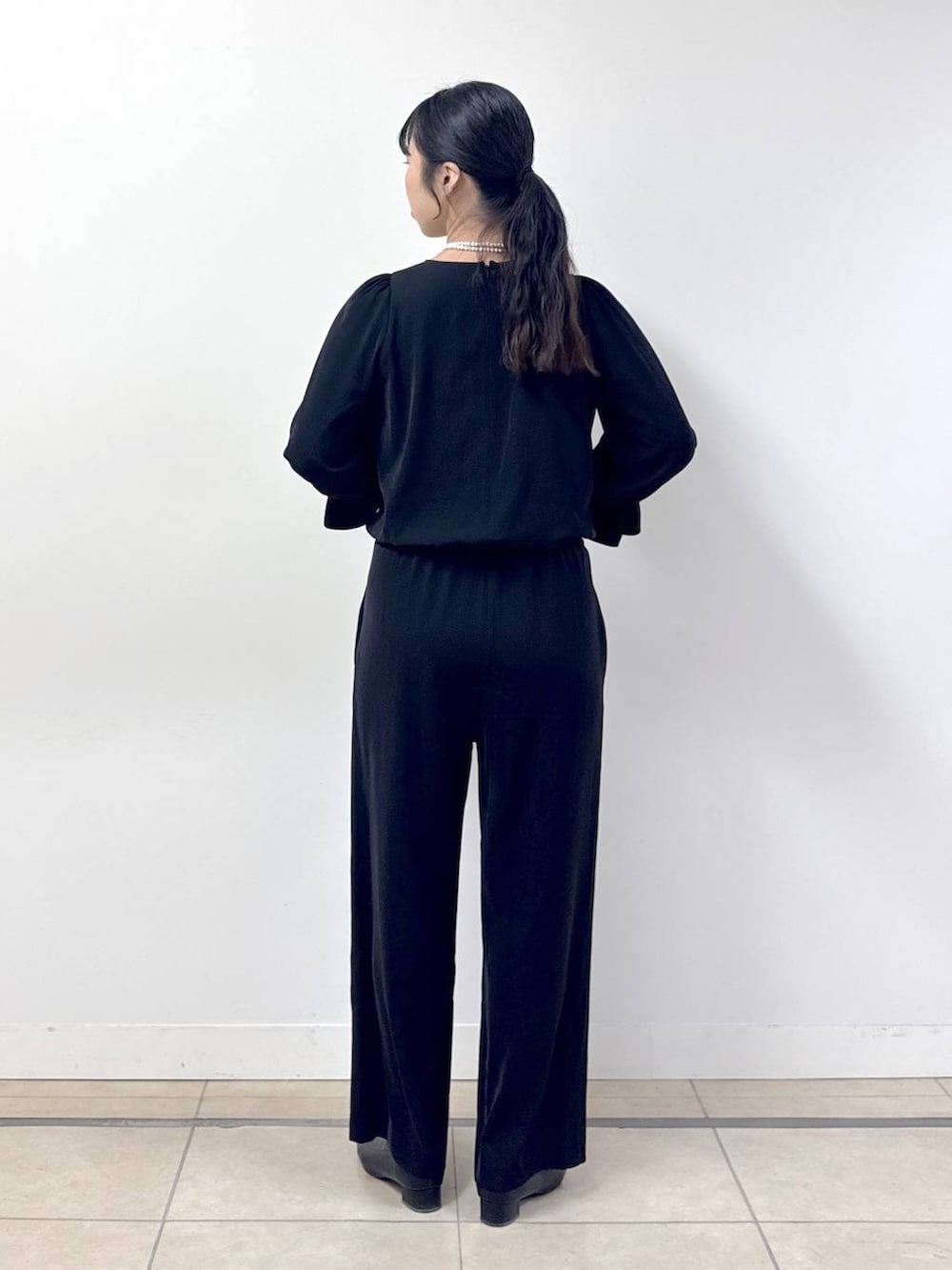 ブラック系のつなぎ/オールインワン、ブラック系のノーカラージャケット、その他のネックレスを着用したレディースの冬コーディネートの6枚目の写真