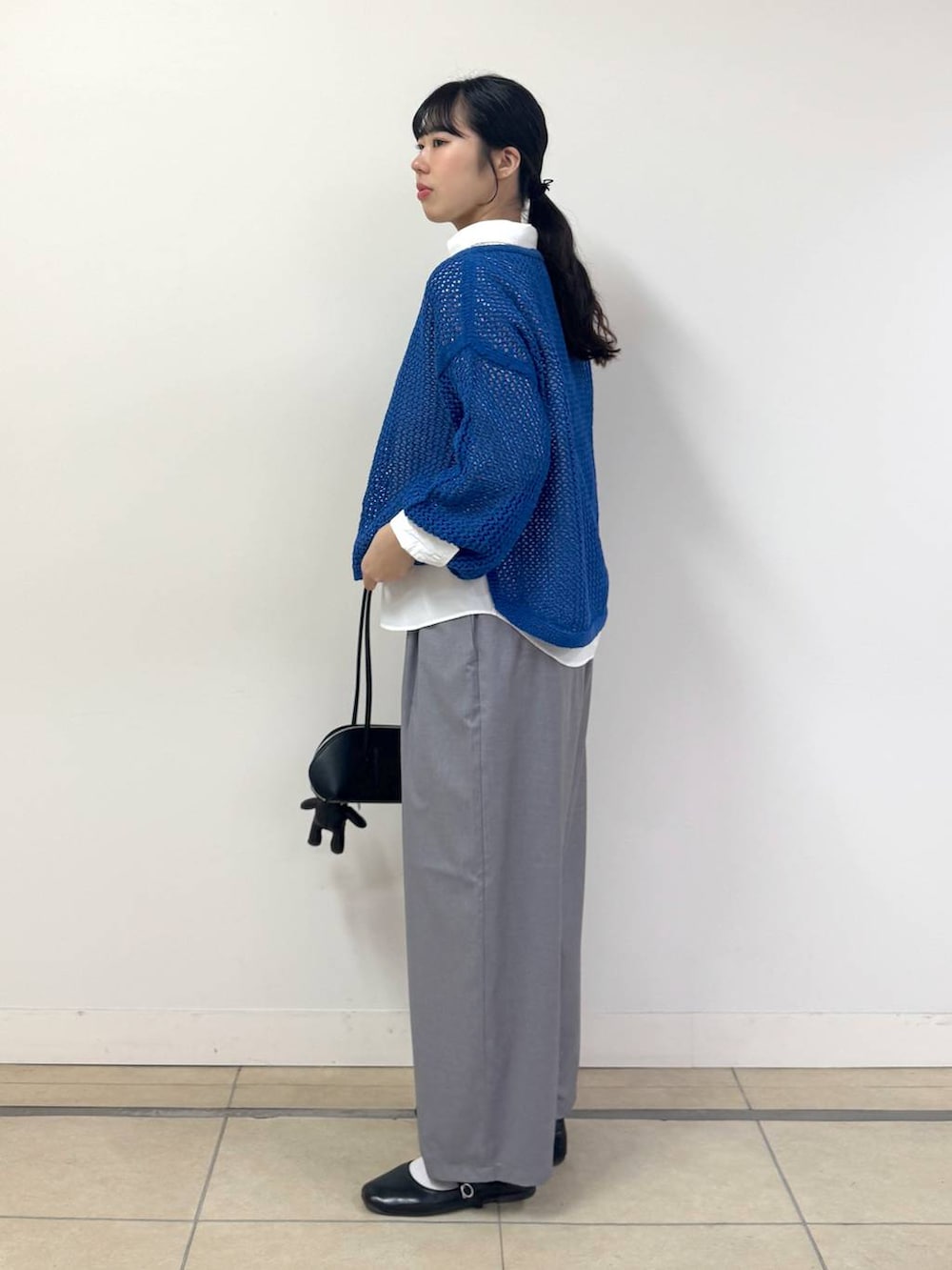 ブルー系のニット/セーター、ホワイト系のシャツ/ブラウス、ブラック系のハンドバッグを着用したレディースの冬コーディネートの2枚目の写真