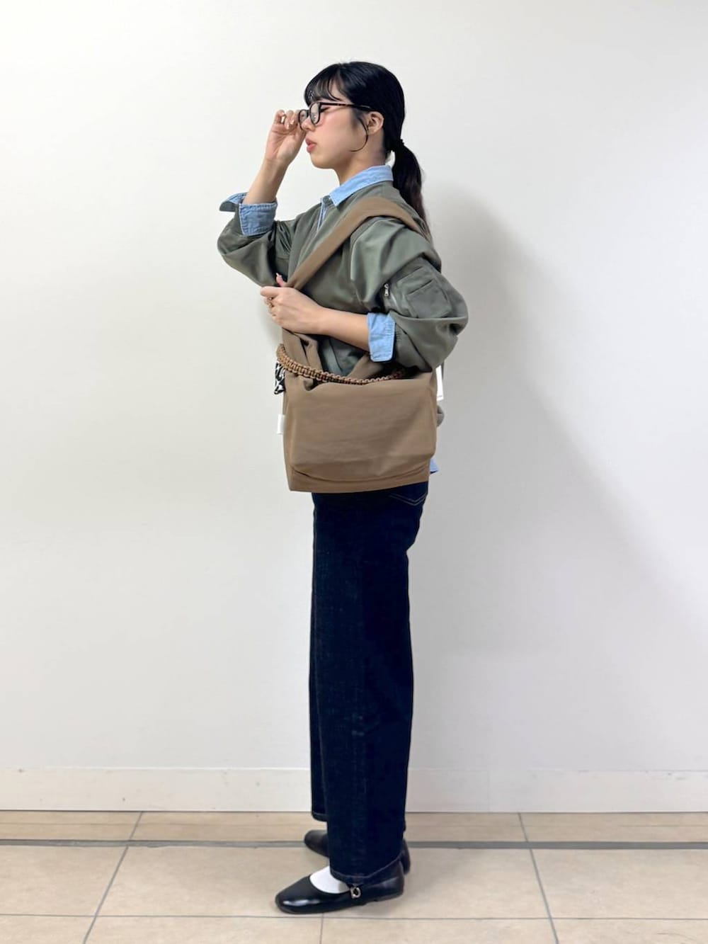 ブルー系のデニムパンツ、ブラウン系のショルダーバッグ、ブルー系のシャツ/ブラウスを着用したレディースの冬コーディネートの2枚目の写真