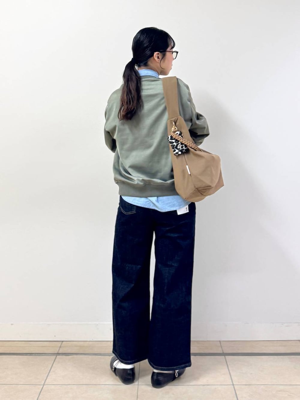 ブルー系のデニムパンツ、ブラウン系のショルダーバッグ、ブルー系のシャツ/ブラウスを着用したレディースの冬コーディネートの3枚目の写真