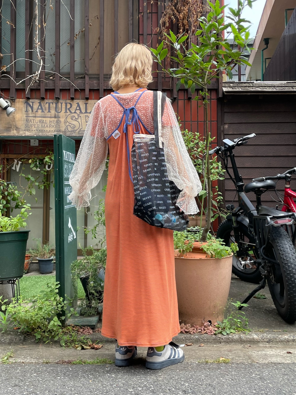 グリーン系のワンピース、グレー系のキャミソール、ブラック系のトートバッグを着用したレディースの夏コーディネートの2枚目の写真