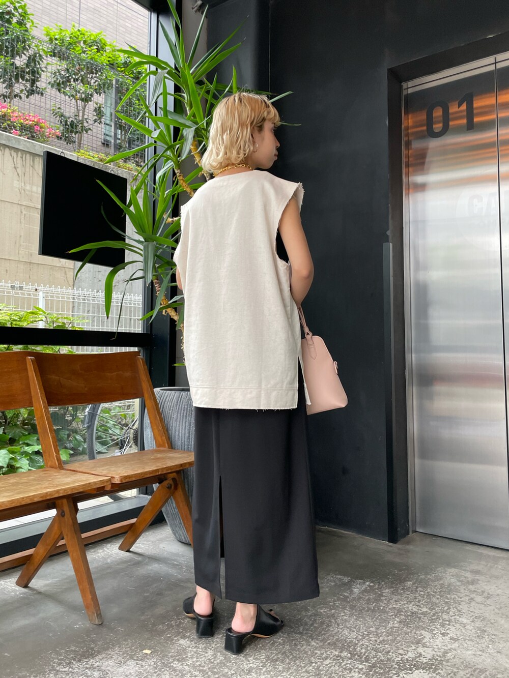 ベージュ系のベスト、ブラック系のワンピース、ピンク系のショルダーバッグを着用したレディースの夏コーディネートの2枚目の写真