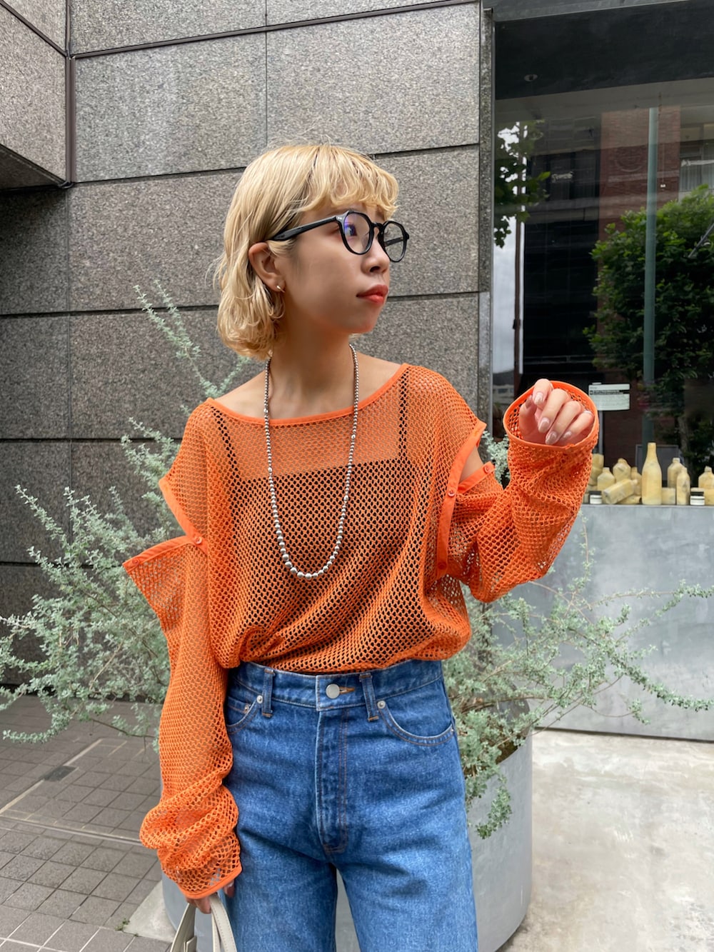 オレンジ系のTシャツ/カットソー、ブルー系のデニムパンツを着用したレディースの夏コーディネートの2枚目の写真