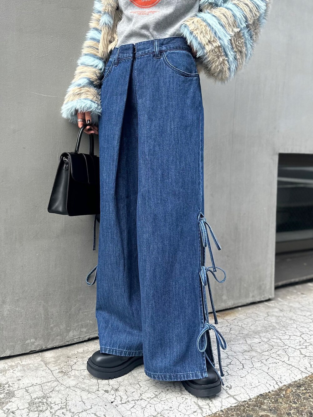 グレー系のキャミソール、グリーン系のカーディガン/ボレロ、ブルー系のデニムパンツを着用したレディースの秋コーディネートの2枚目の写真