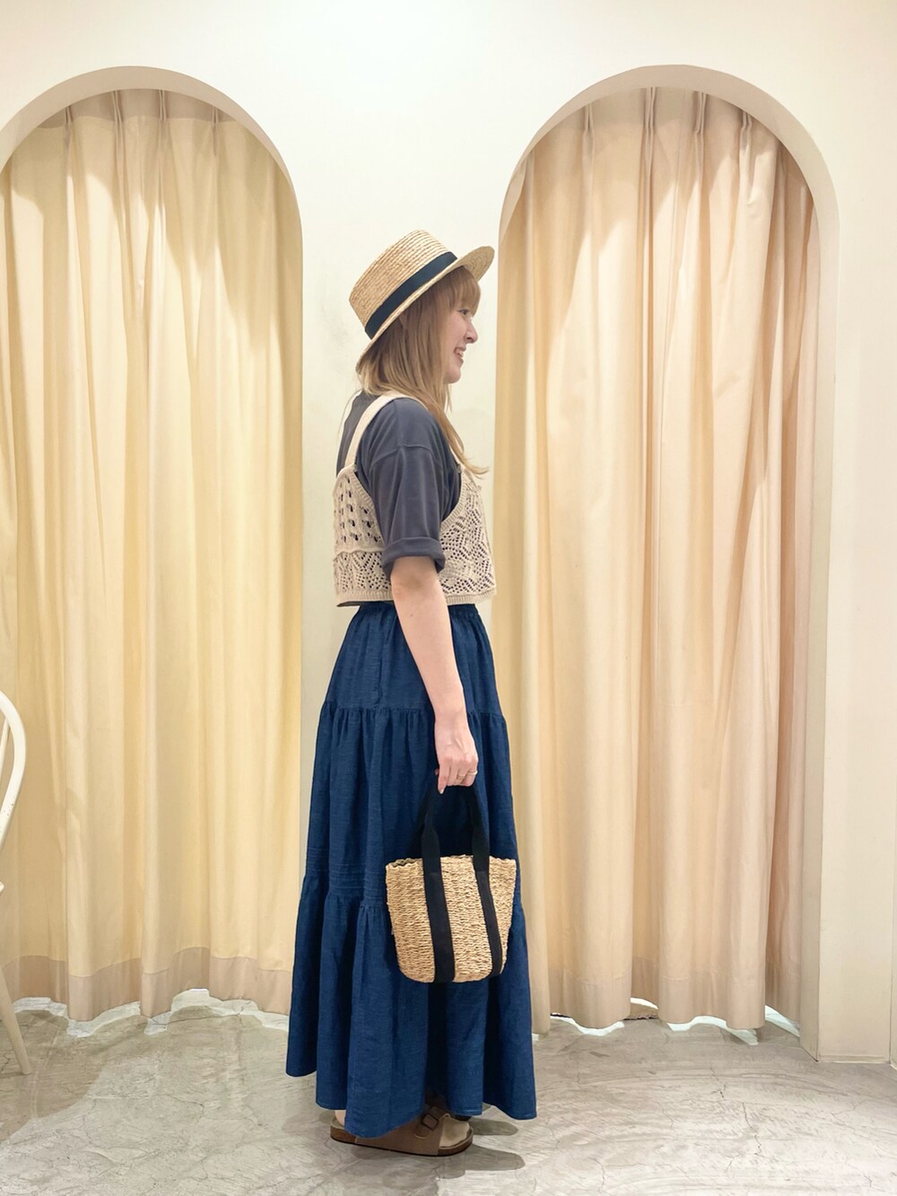 ブラック系のハンドバッグ、ベージュ系のベスト、グレー系のTシャツ/カットソーを着用したレディースの夏コーディネートの4枚目の写真