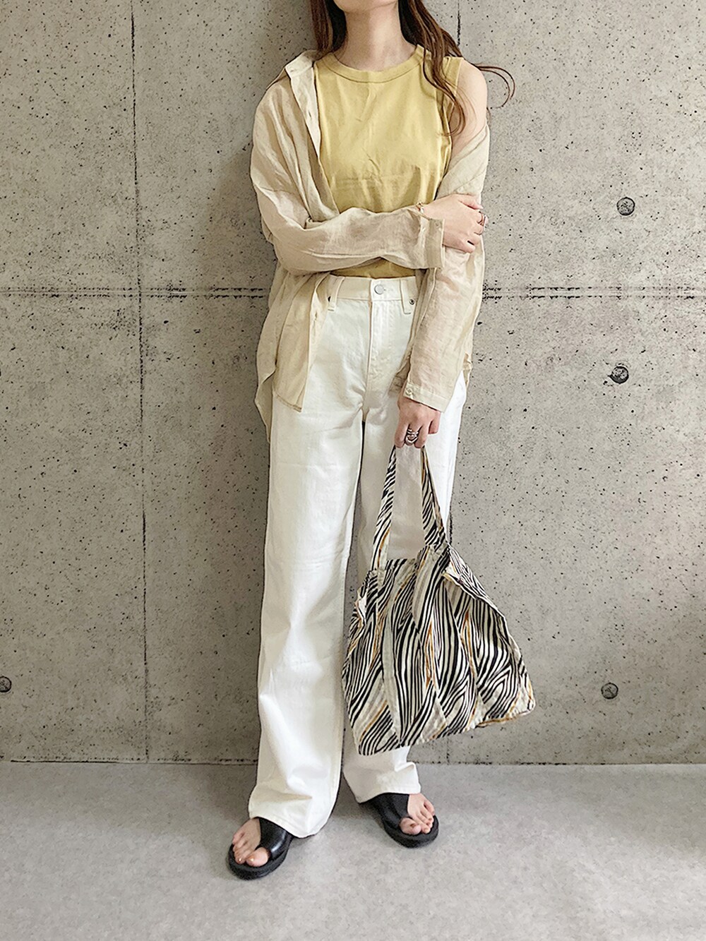 ブラック系のサンダル、ベージュ系のトートバッグ、ホワイト系のデニムパンツを着用したレディースの夏コーディネートの2枚目の写真