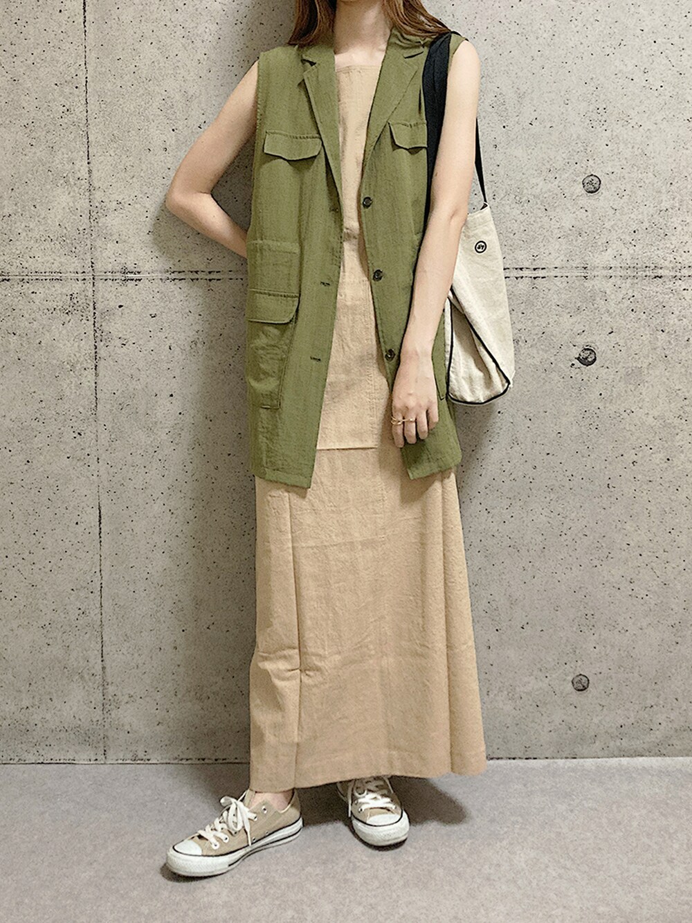 ベージュ系のスニーカー、ベージュ系のワンピース、グリーン系のベストを着用したレディースの夏コーディネートの2枚目の写真