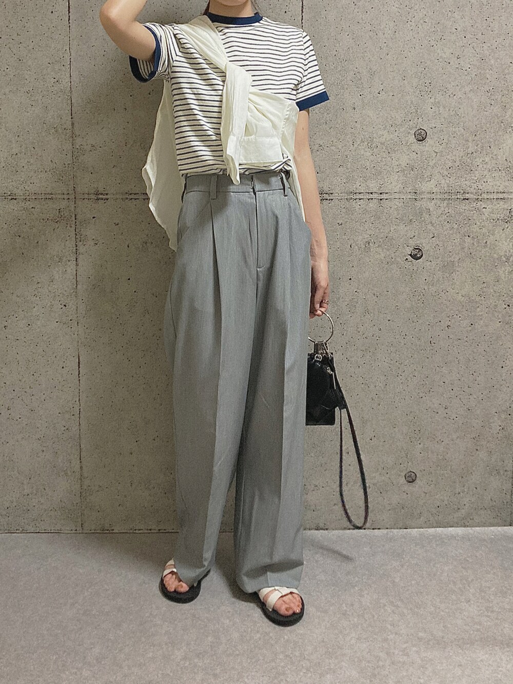 ブラック系のショルダーバッグ、グレー系のスラックス、ホワイト系のサンダルを着用したレディースの夏コーディネートの2枚目の写真