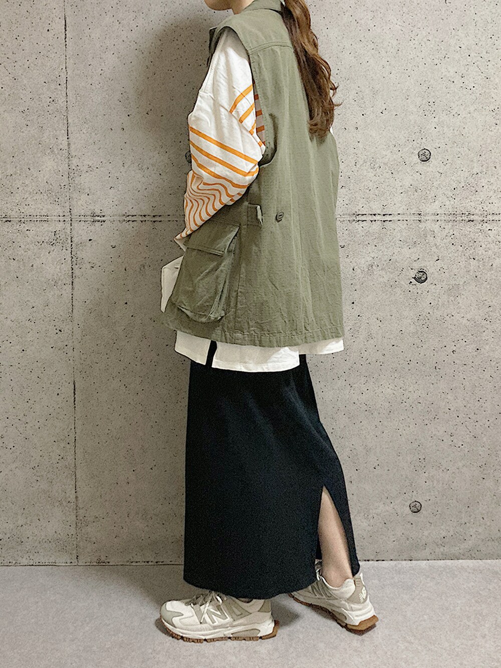 ベージュ系のスニーカー、ブラック系のスカート、グリーン系のベストを着用したレディースの秋コーディネートの2枚目の写真