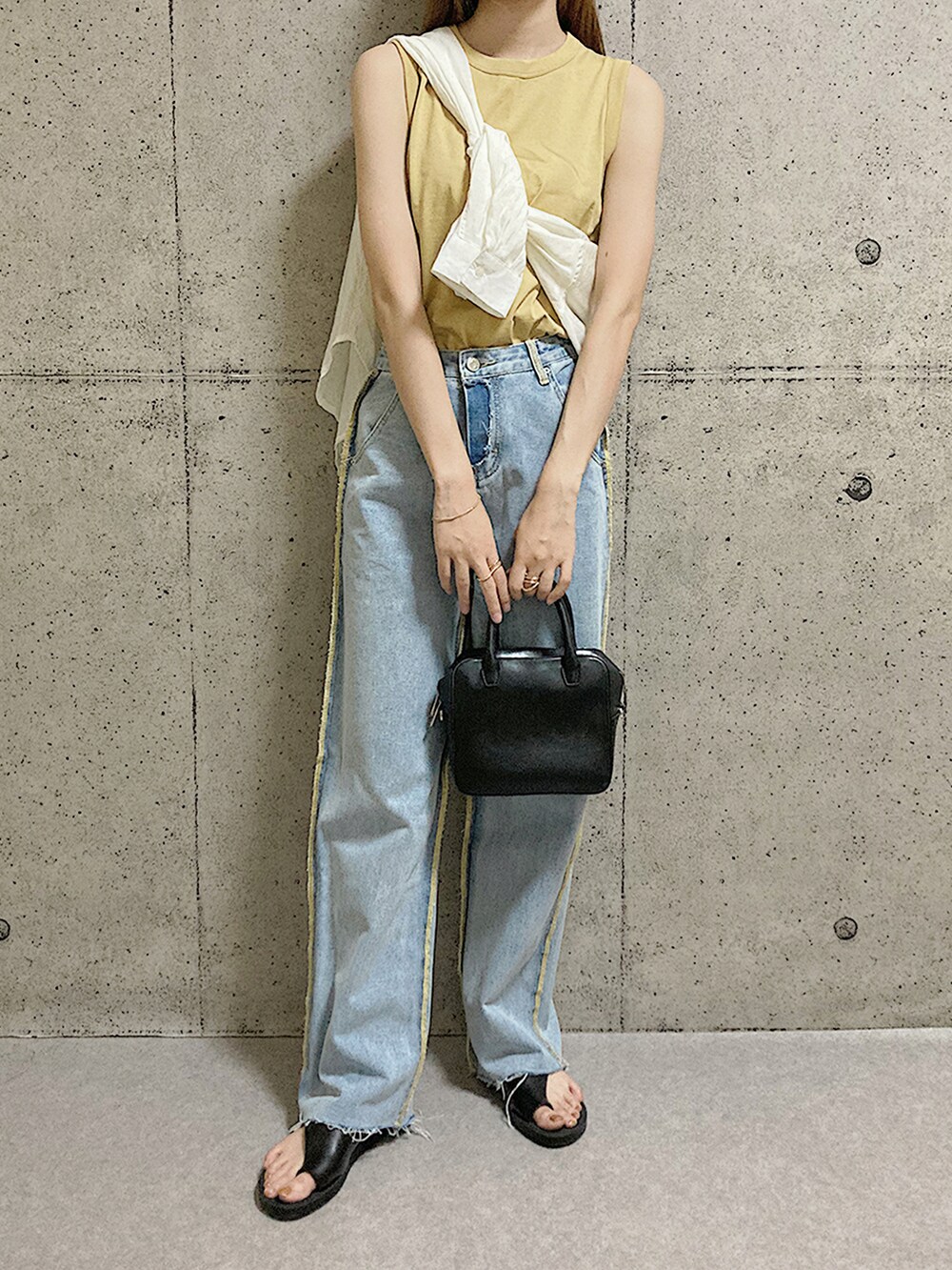 ブラック系のサンダル、ブルー系のデニムパンツ、イエロー系のタンクトップを着用したレディースの夏コーディネートの2枚目の写真