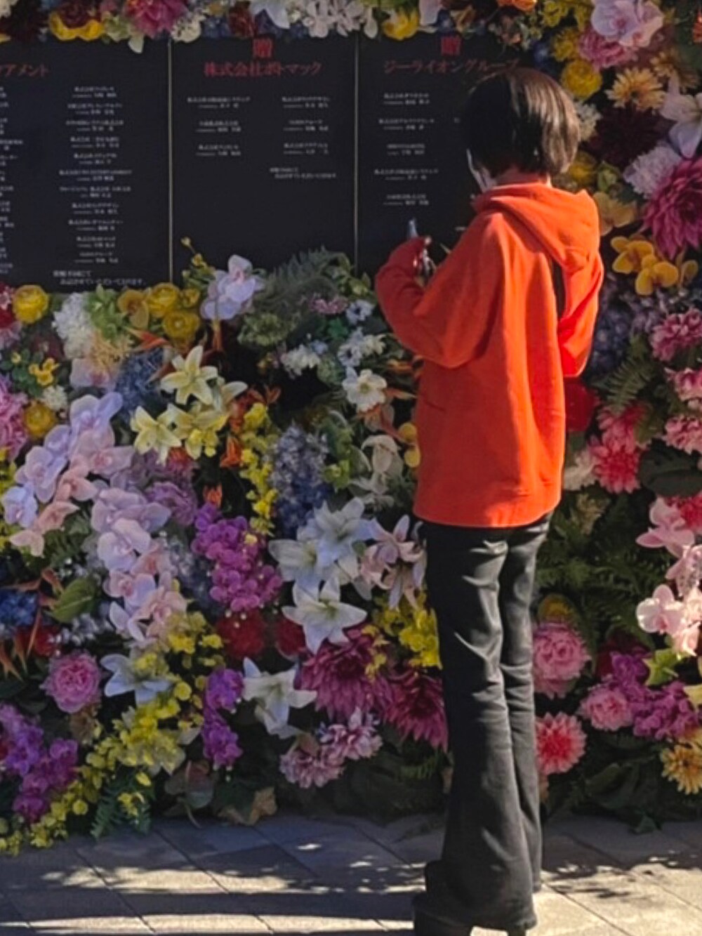 オレンジ系のトップス、ブラック系のデニムパンツ、ブラック系のブーツを着用したレディースの秋コーディネートの2枚目の写真