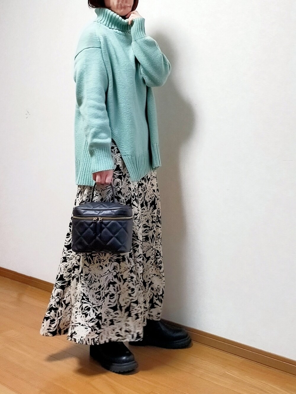 グリーン系のニット/セーター、ブラック系のスカート、ブラック系のブーツを着用したレディースの冬コーディネートの2枚目の写真