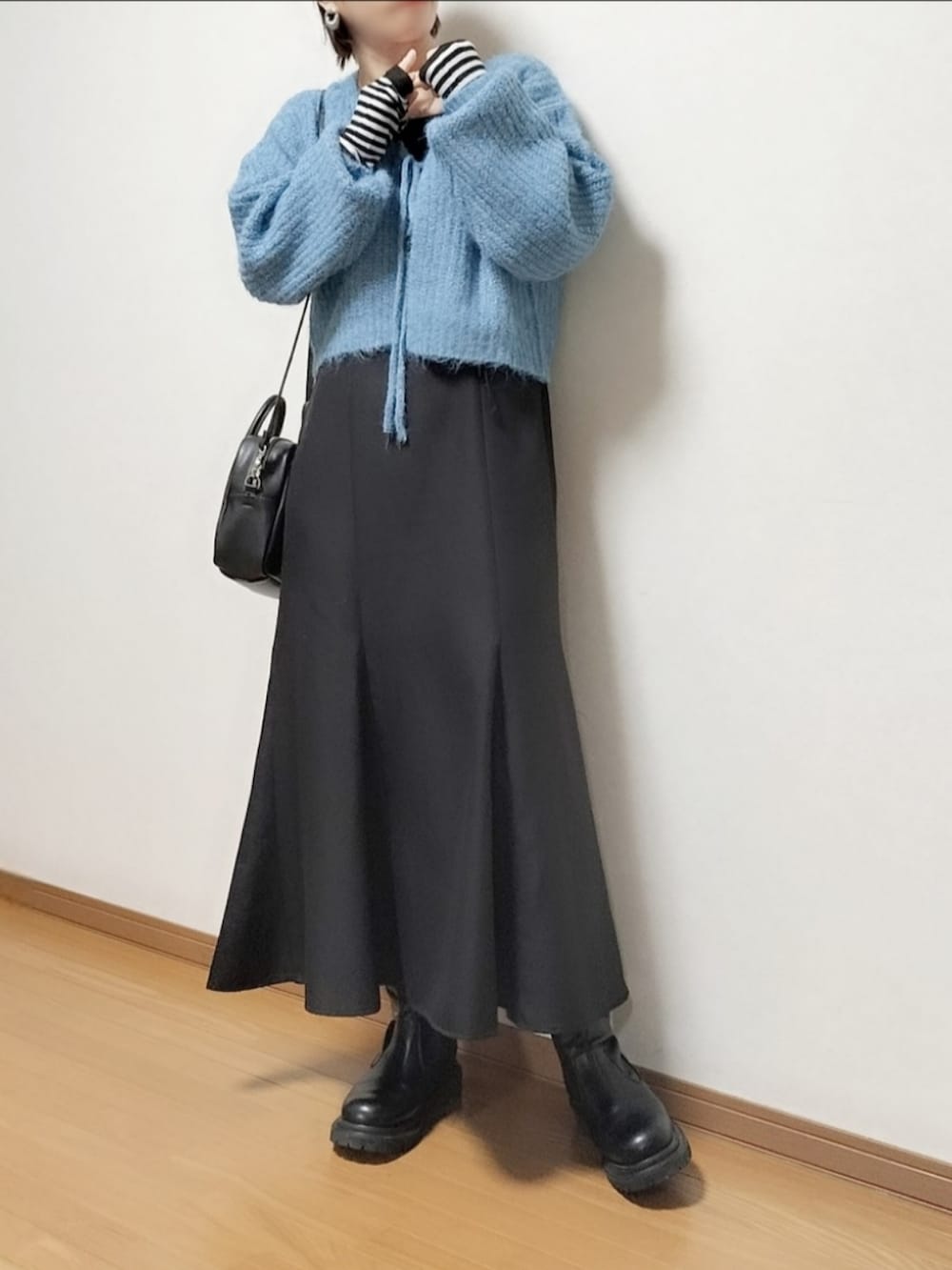 ブルー系のアンサンブル、ブラック系のジャンパースカート、ブラック系のブーツを着用したレディースの秋コーディネートの2枚目の写真