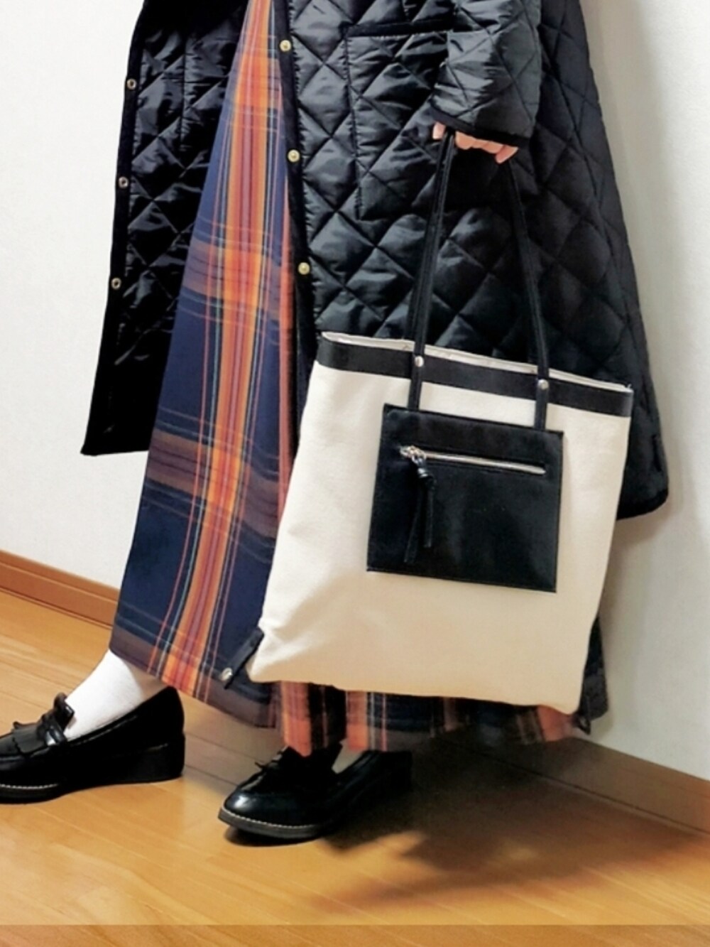 ブラック系のその他アウター、ブルー系のスカート、ベージュ系のニット/セーターを着用したレディースの冬コーディネートの2枚目の写真