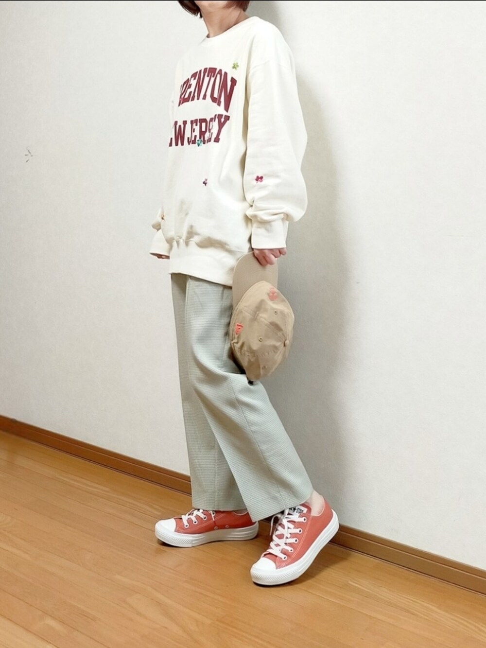 ホワイト系のスウェット、オレンジ系のスニーカー、ベージュ系のキャップを着用したレディースの春コーディネートの2枚目の写真