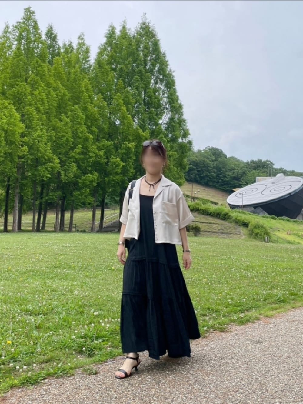 ブラック系のワンピース、ブラック系のサンダル、ベージュ系のシャツ/ブラウスを着用したレディースの夏コーディネートの2枚目の写真