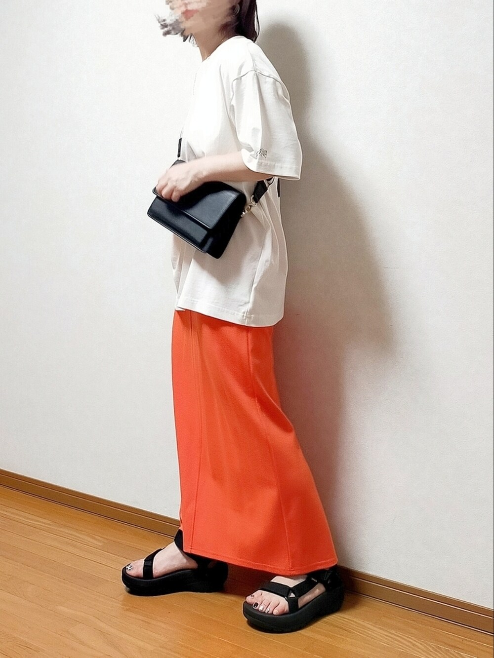 レッド系のスカート、ホワイト系のTシャツ/カットソー、ブラック系のショルダーバッグを着用したレディースの夏コーディネートの2枚目の写真