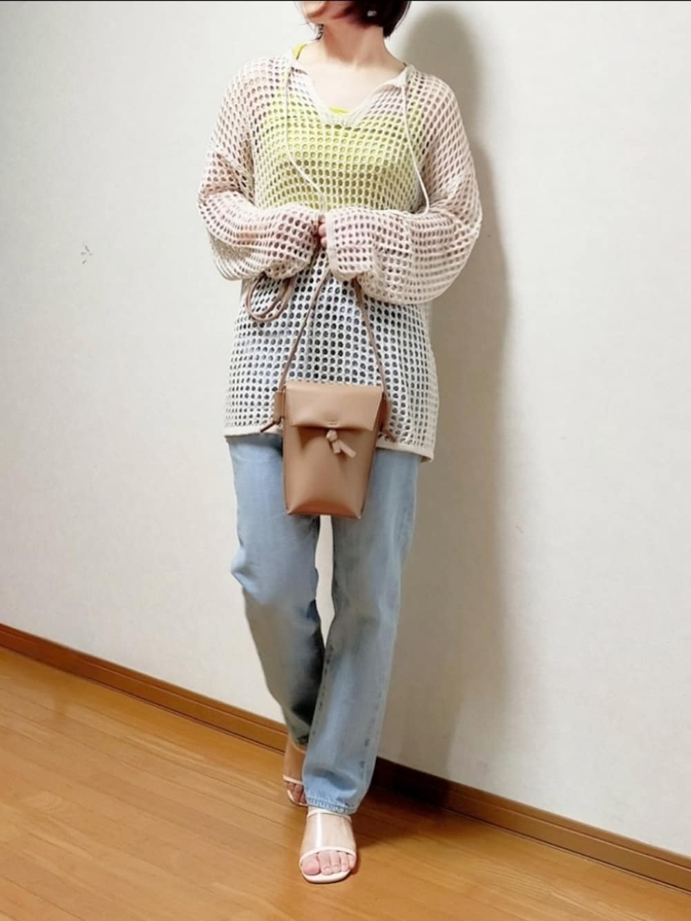 ブルー系のデニムパンツ、ベージュ系のショルダーバッグ、ホワイト系のニット/セーターを着用したレディースの春コーディネートの2枚目の写真