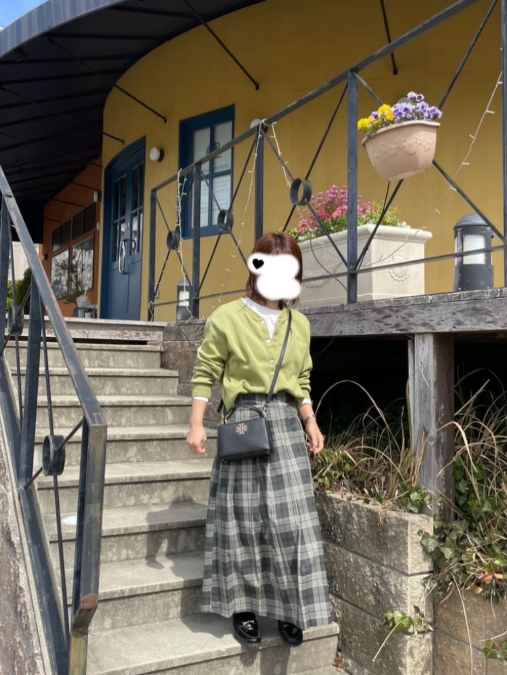 グレー系のスカート、ホワイト系のTシャツ/カットソー、グリーン系のカーディガン/ボレロを着用したレディースの春コーディネートの2枚目の写真