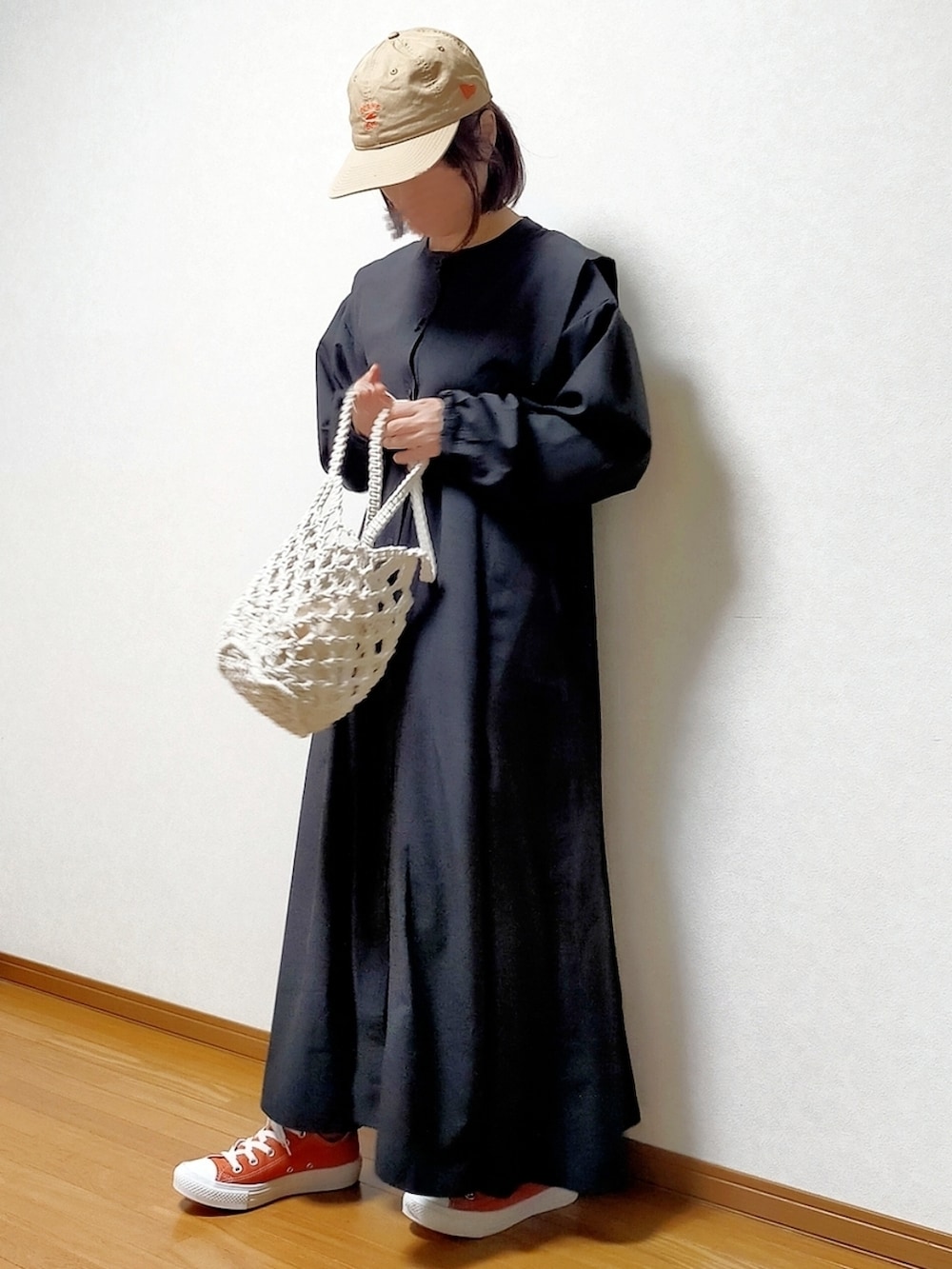 ブラック系のシャツワンピース、オレンジ系のスニーカー、ホワイト系のトートバッグを着用したレディースの春コーディネートの2枚目の写真