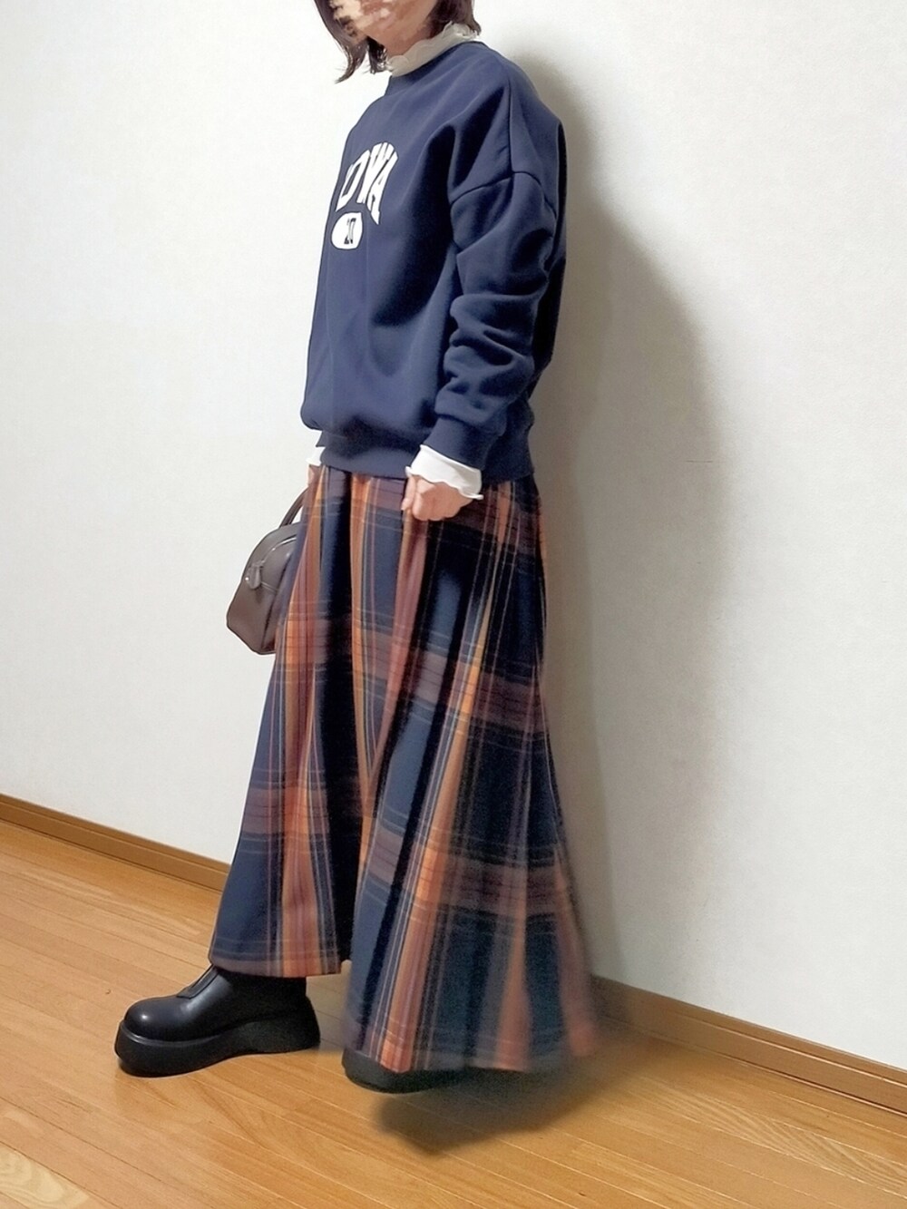 ブラック系のブーツ、ブルー系のスカート、ホワイト系のTシャツ/カットソーを着用したレディースの秋コーディネートの2枚目の写真