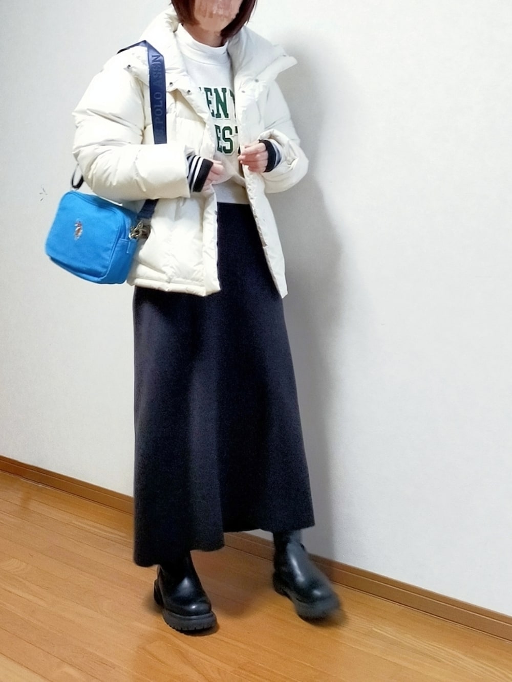 ブルー系のショルダーバッグ、ホワイト系のダウンジャケット/コート、ブラック系のスカートを着用したレディースの冬コーディネートの3枚目の写真