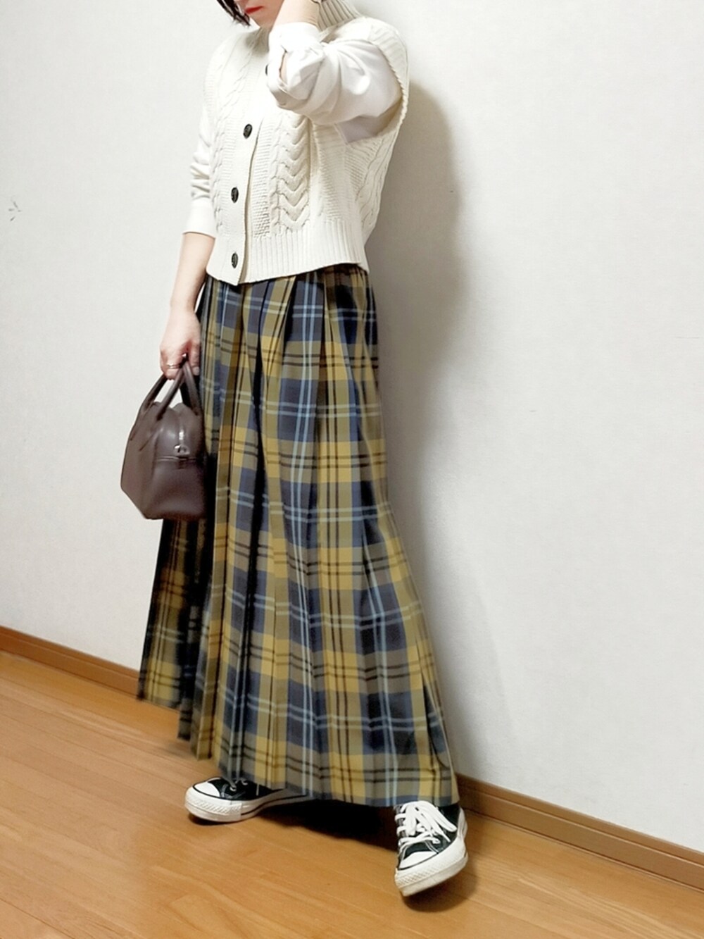 ホワイト系のニット/セーター、イエロー系のスカート、ブラック系のスニーカーを着用したレディースの春コーディネートの2枚目の写真