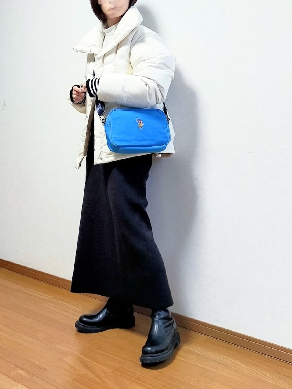 ブルー系のショルダーバッグ、ホワイト系のダウンジャケット/コート、ブラック系のスカートを着用したレディースの冬コーディネートの2枚目の写真