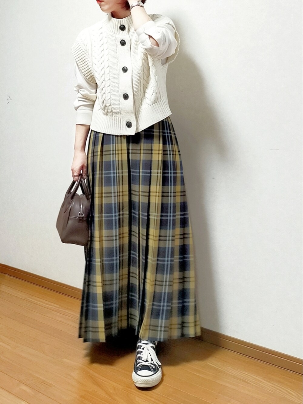 ホワイト系のニット/セーター、イエロー系のスカート、ブラック系のスニーカーを着用したレディースの春コーディネートの3枚目の写真