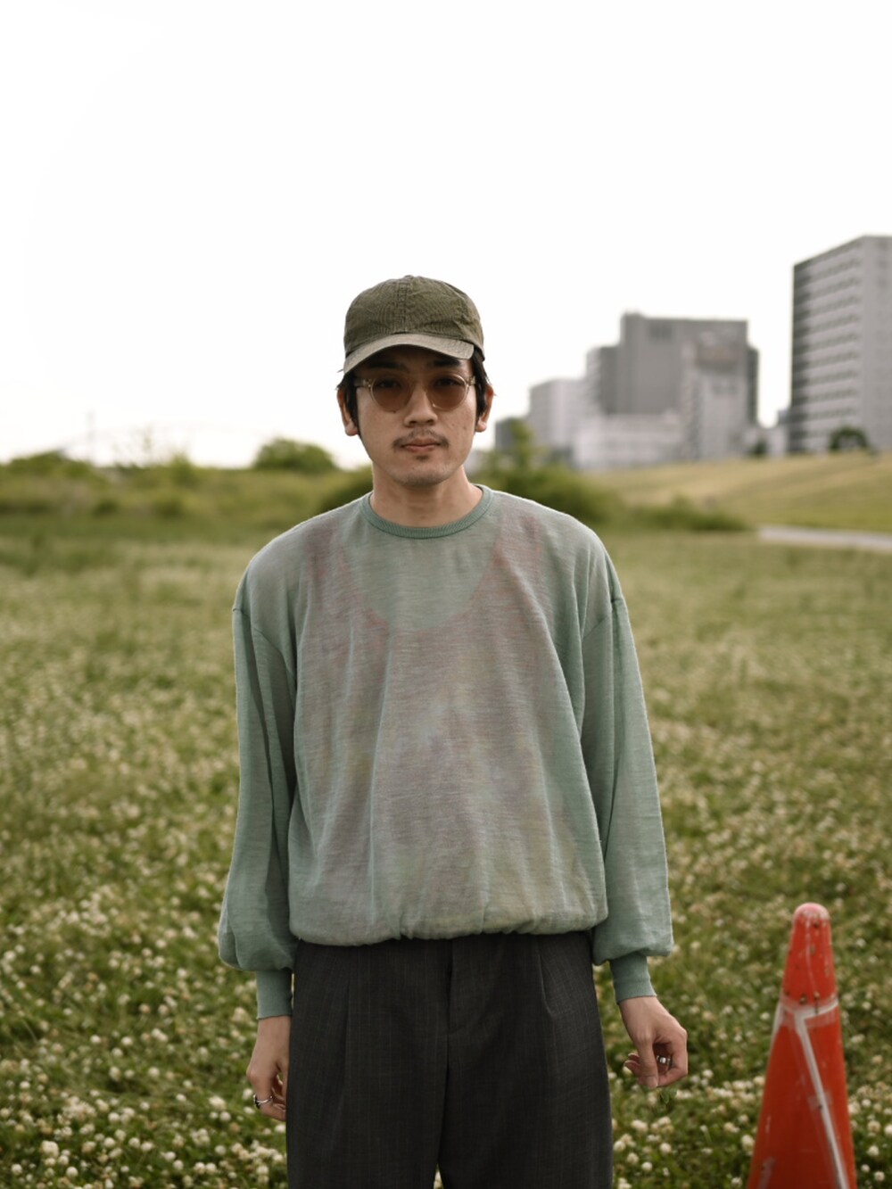 グレー系のパンツ、ブラック系のサンダル、グリーン系のトップスを着用したメンズの春コーディネートの2枚目の写真