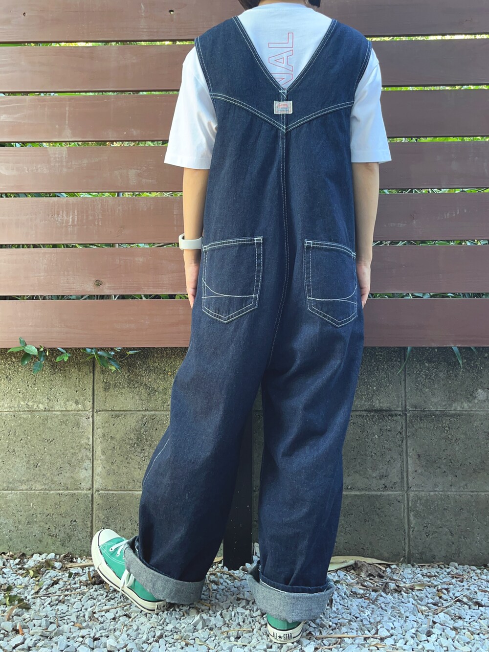 グリーン系のスニーカー、ブルー系のサロペット/オーバーオール、ホワイト系のTシャツ/カットソーを着用したレディースの秋コーディネートの2枚目の写真