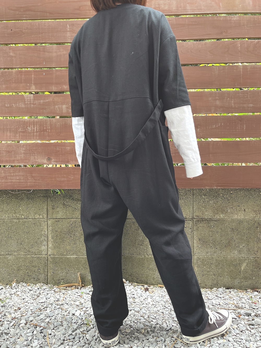 ブラック系のスニーカー、ブラック系のサロペット/オーバーオール、ホワイト系のTシャツ/カットソーを着用したレディースの春コーディネートの2枚目の写真