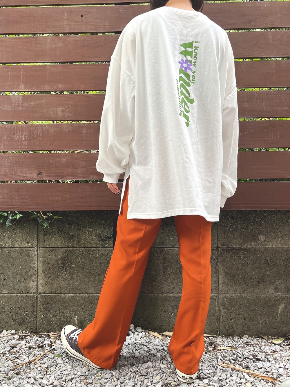 ホワイト系のTシャツ/カットソー、オレンジ系のその他パンツ、ブラック系のスニーカーを着用したレディースの秋コーディネートの2枚目の写真