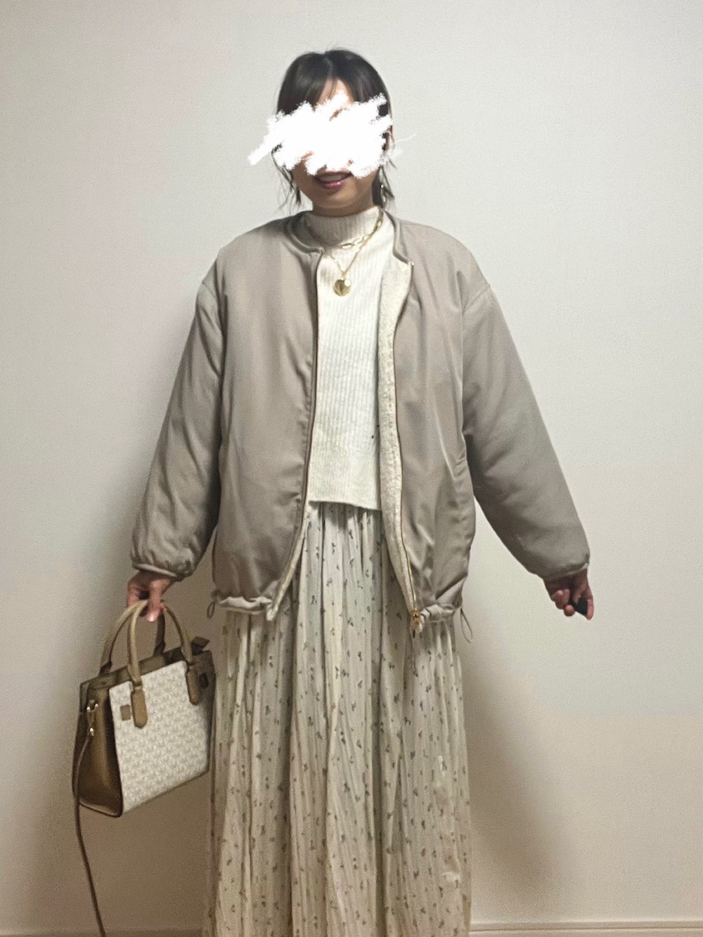 ベージュ系のスカート、ホワイト系のニット/セーター、ベージュ系のショルダーバッグを着用したレディースの冬コーディネートの2枚目の写真