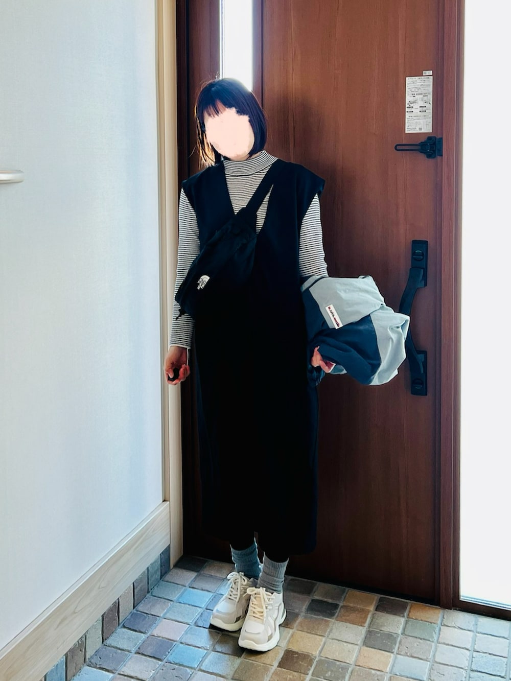 ブラック系のボディバッグ/ウエストポーチ、ブラック系のジャンパースカート、ベージュ系のスニーカーを着用したレディースの春コーディネートの3枚目の写真