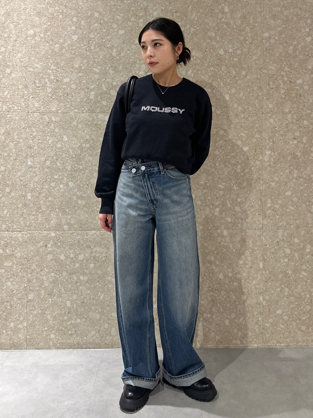 ブルー系のデニムパンツ、ブラック系のブーツ、ブラック系のトートバッグを着用したレディースの秋コーディネートの2枚目の写真