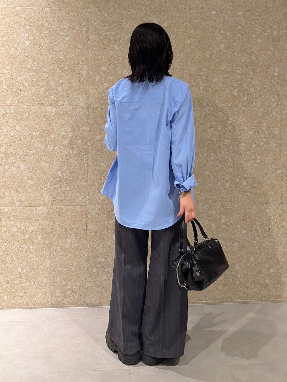 ブルー系のアンサンブル、グレー系のスラックス、ブラック系のショルダーバッグを着用したレディースの春コーディネートの5枚目の写真