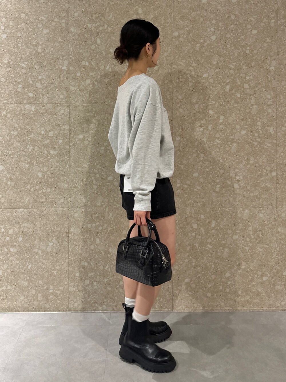 グレー系のスウェット、ブラック系のデニムパンツ、ブラック系のブーツを着用したレディースの秋コーディネートの4枚目の写真