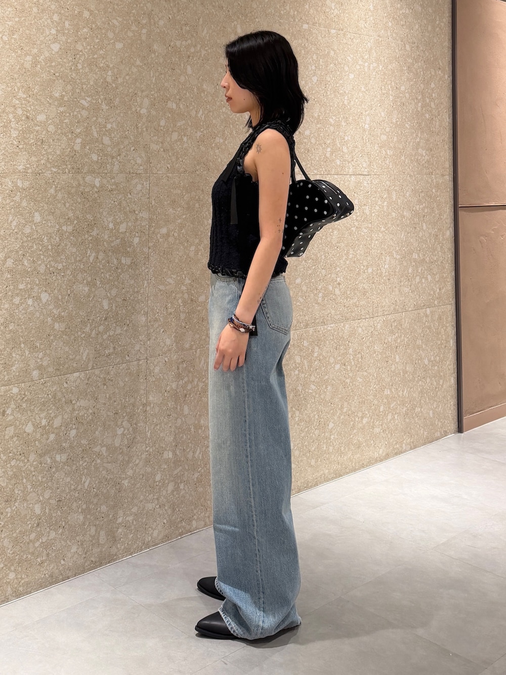 ブルー系のデニムパンツ、ブラック系のタンクトップ、ブラック系のブーツを着用したレディースの夏コーディネートの3枚目の写真