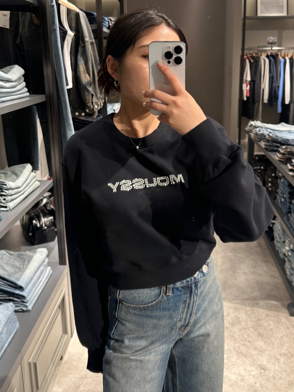 ブルー系のデニムパンツ、ブラック系のブーツ、ブラック系のトートバッグを着用したレディースの秋コーディネートの5枚目の写真