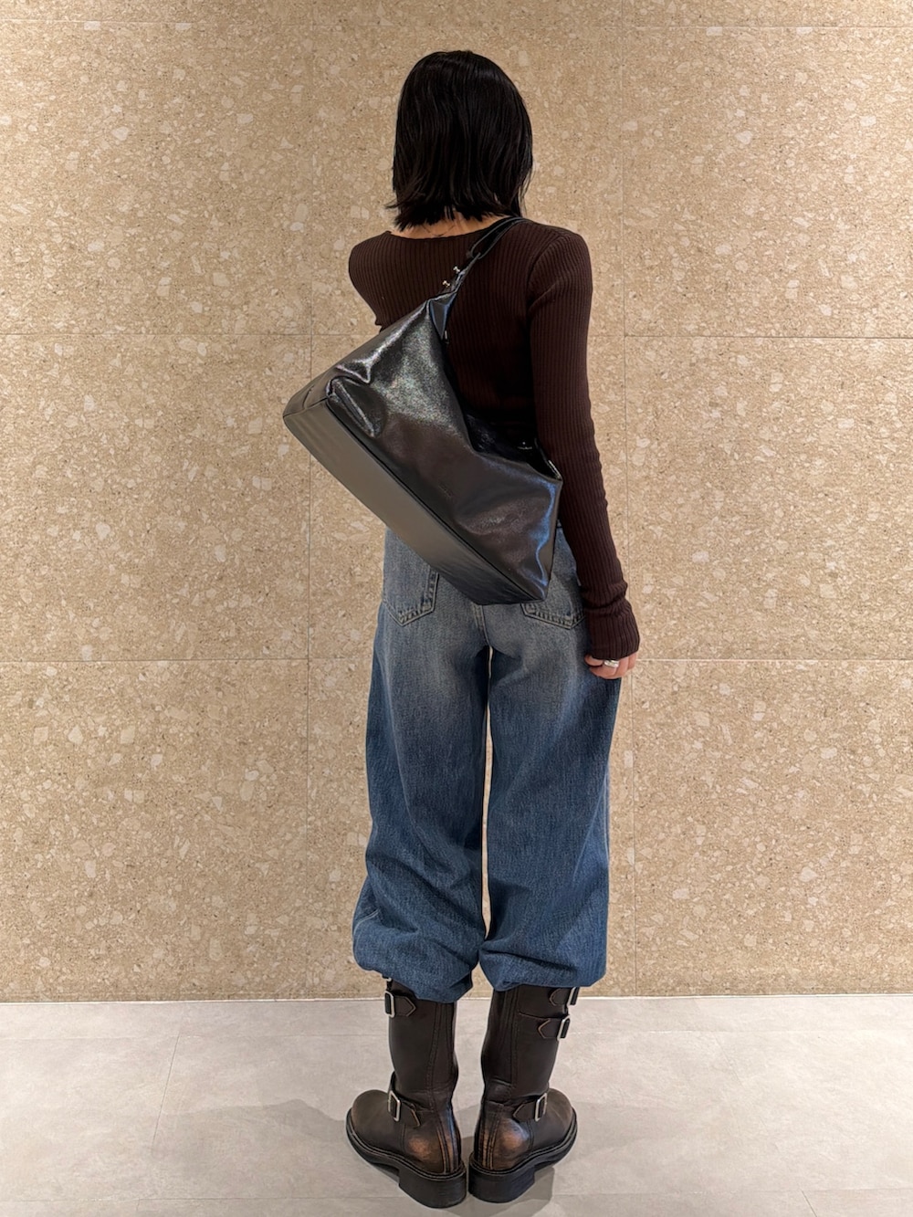 ブラウン系のブーツ、ブラック系のショルダーバッグ、ブルー系のデニムパンツを着用したレディースの冬コーディネートの3枚目の写真