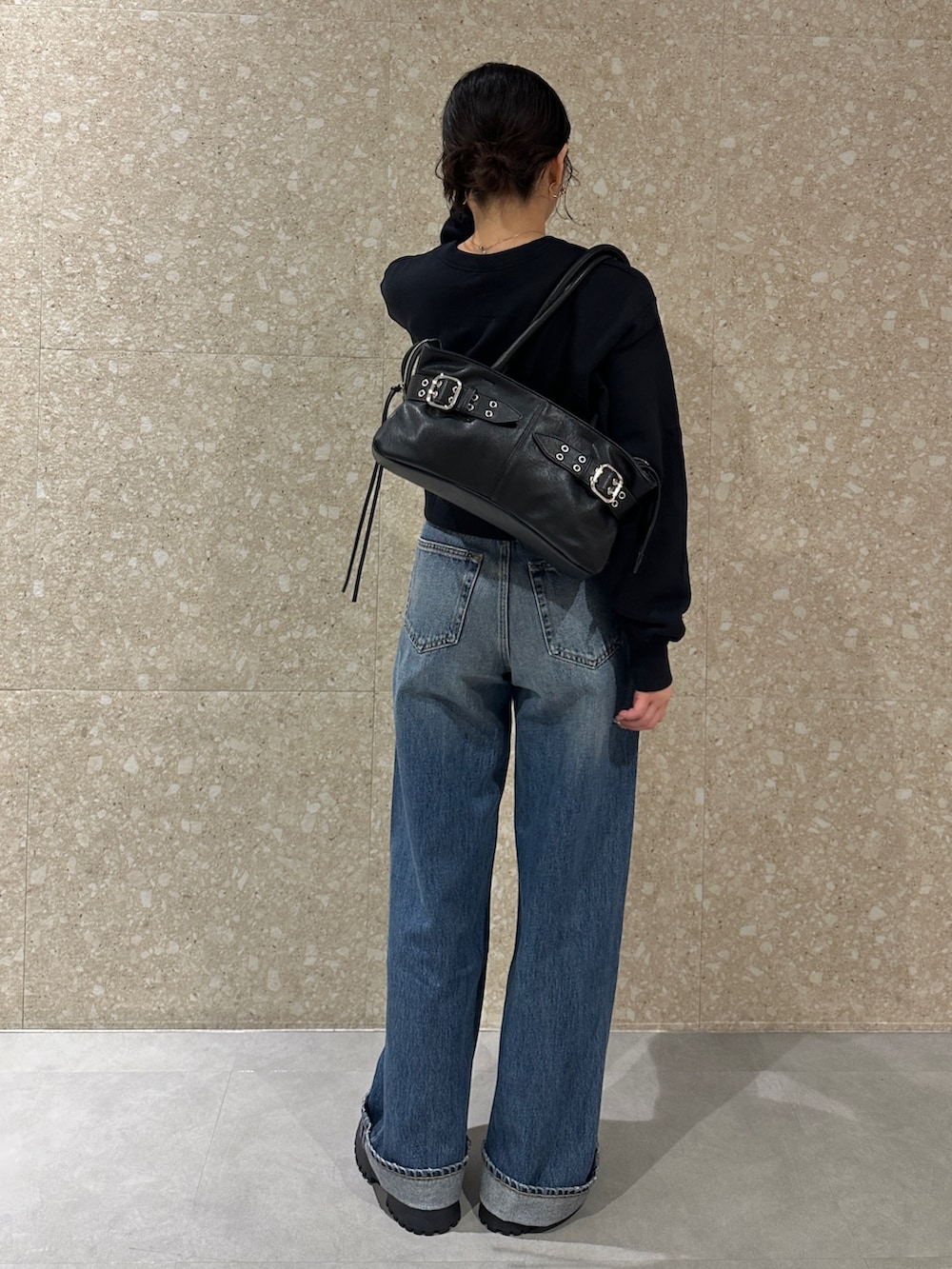 ブルー系のデニムパンツ、ブラック系のブーツ、ブラック系のトートバッグを着用したレディースの秋コーディネートの3枚目の写真