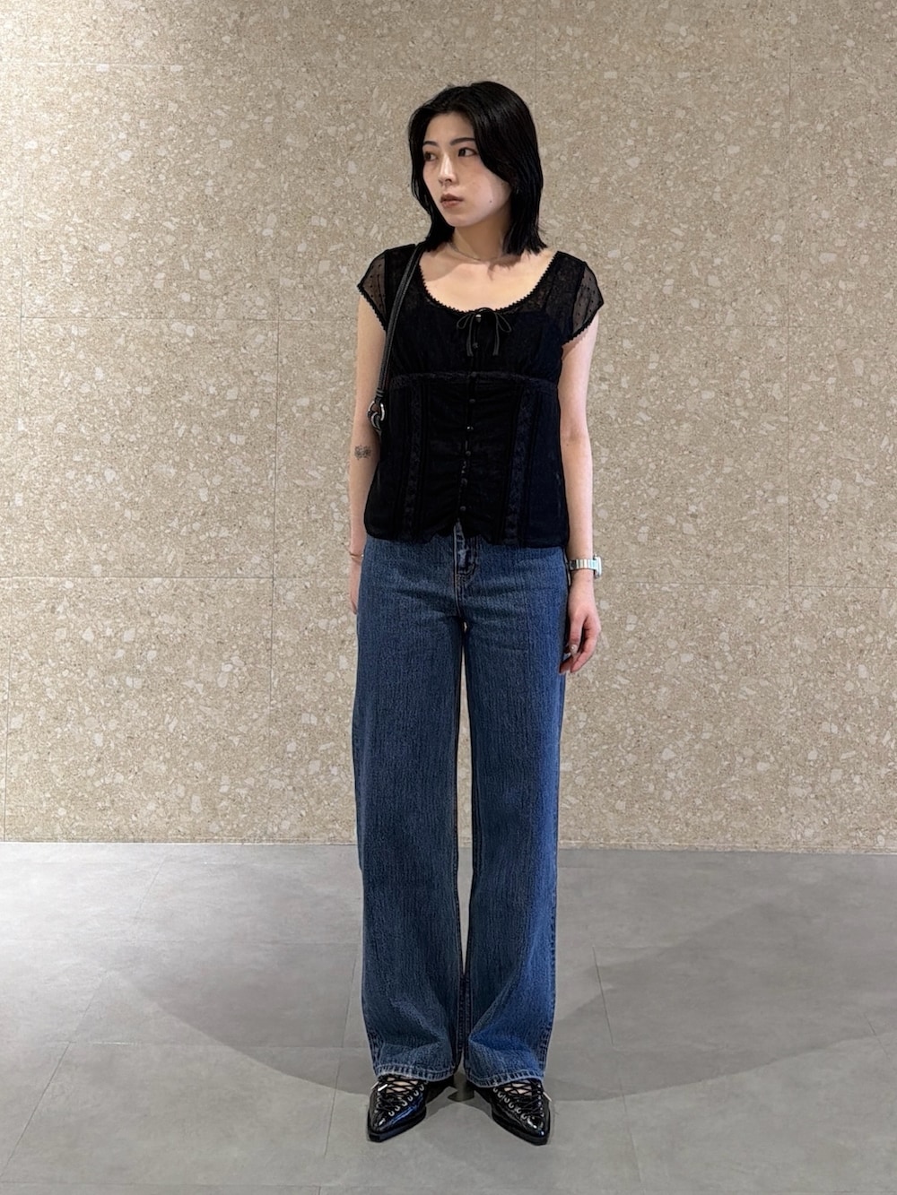 ブルー系のデニムパンツ、ブラック系のシャツ/ブラウス、ブラック系のショルダーバッグを着用したレディースの春コーディネートの2枚目の写真