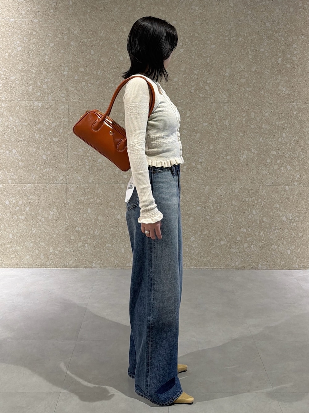 ホワイト系のニット/セーター、ブルー系のデニムパンツ、ベージュ系のサンダルを着用したレディースの春コーディネートの3枚目の写真