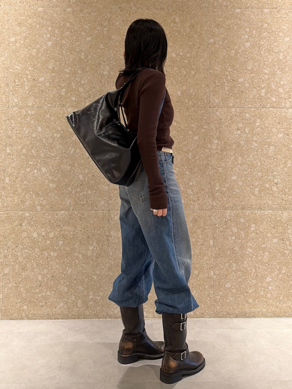 ブラウン系のブーツ、ブラック系のショルダーバッグ、ブルー系のデニムパンツを着用したレディースの冬コーディネートの4枚目の写真