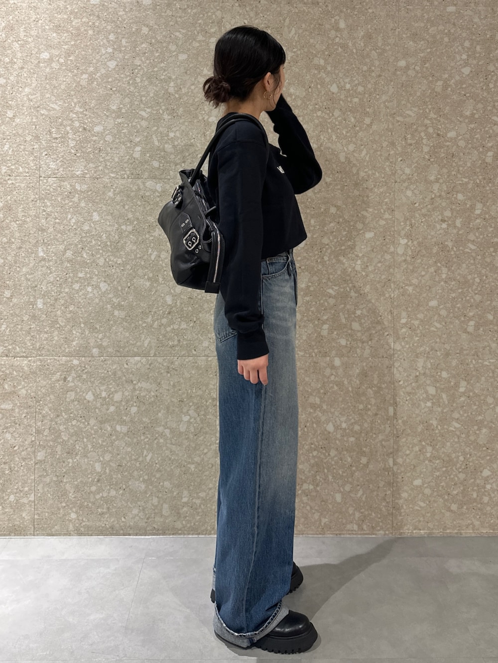 ブルー系のデニムパンツ、ブラック系のブーツ、ブラック系のトートバッグを着用したレディースの秋コーディネートの4枚目の写真
