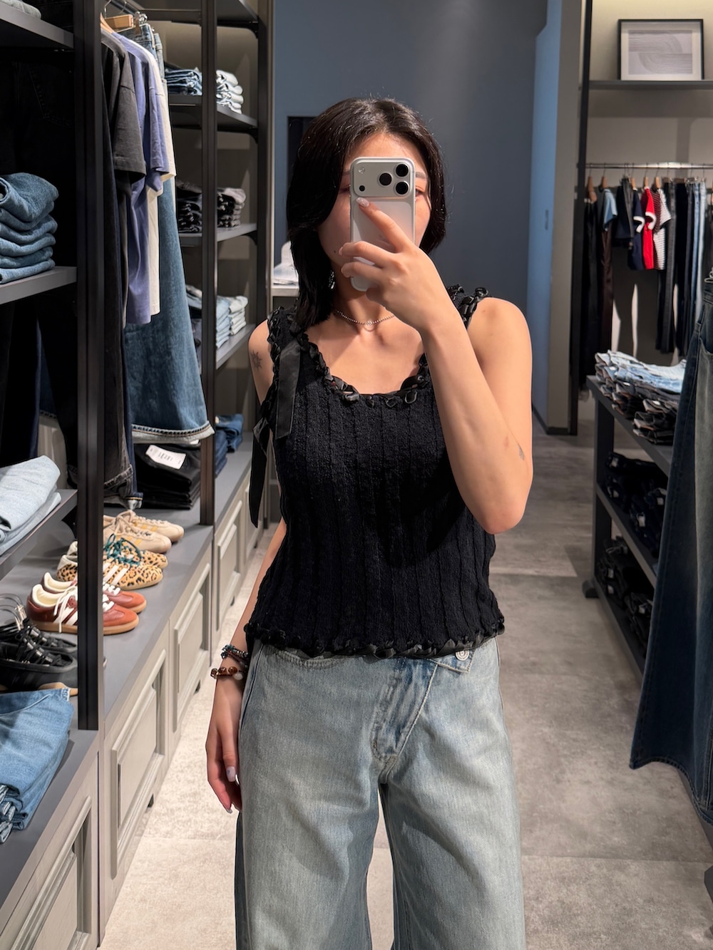 ブルー系のデニムパンツ、ブラック系のタンクトップ、ブラック系のブーツを着用したレディースの夏コーディネートの5枚目の写真