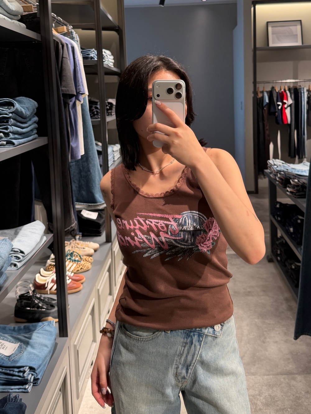 ブルー系のデニムパンツ、ブラック系のブーツ、ブラウン系のタンクトップを着用したレディースの夏コーディネートの5枚目の写真