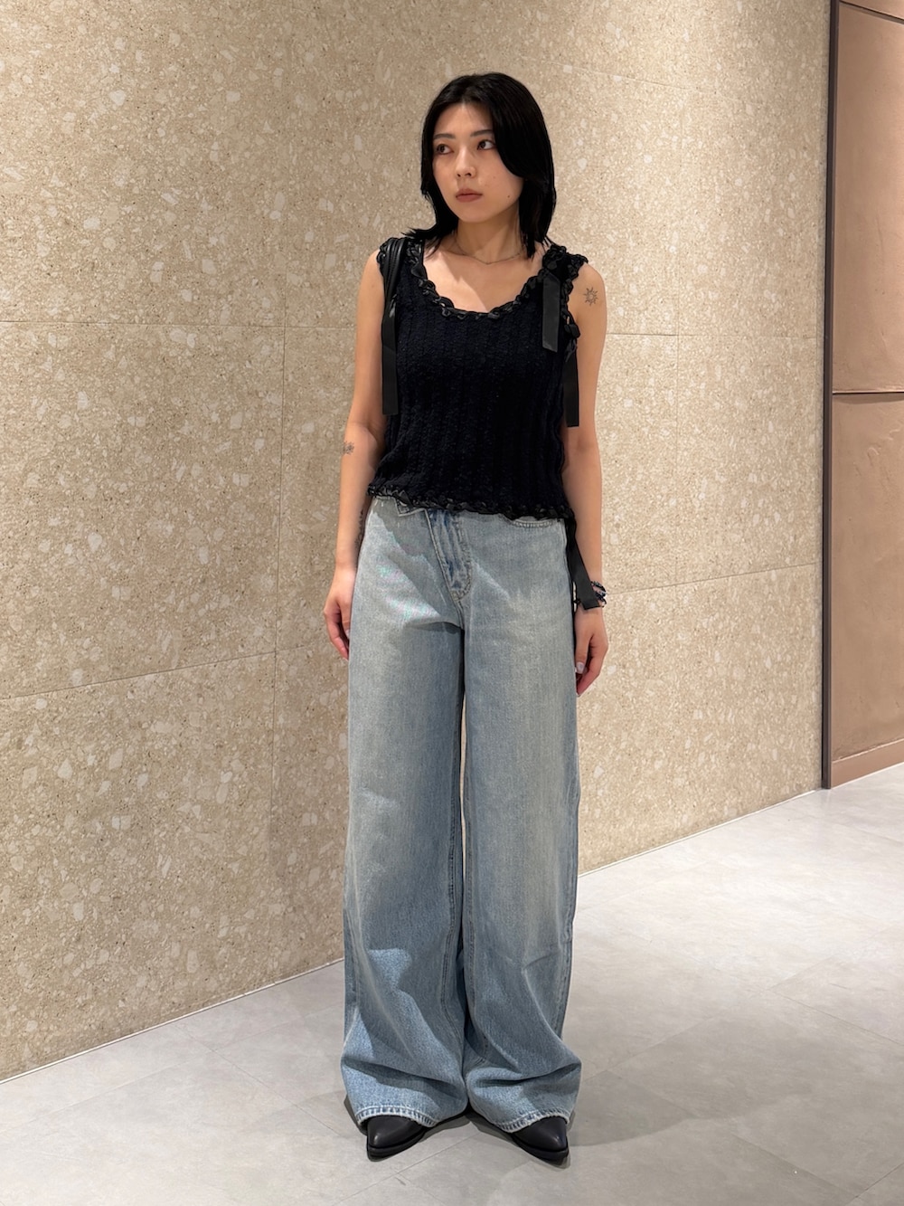 ブルー系のデニムパンツ、ブラック系のタンクトップ、ブラック系のブーツを着用したレディースの夏コーディネートの2枚目の写真